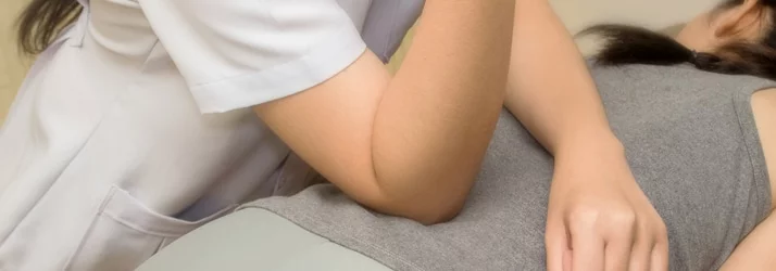 A practitioner using physical therapy and massage methods on a patient's lower back