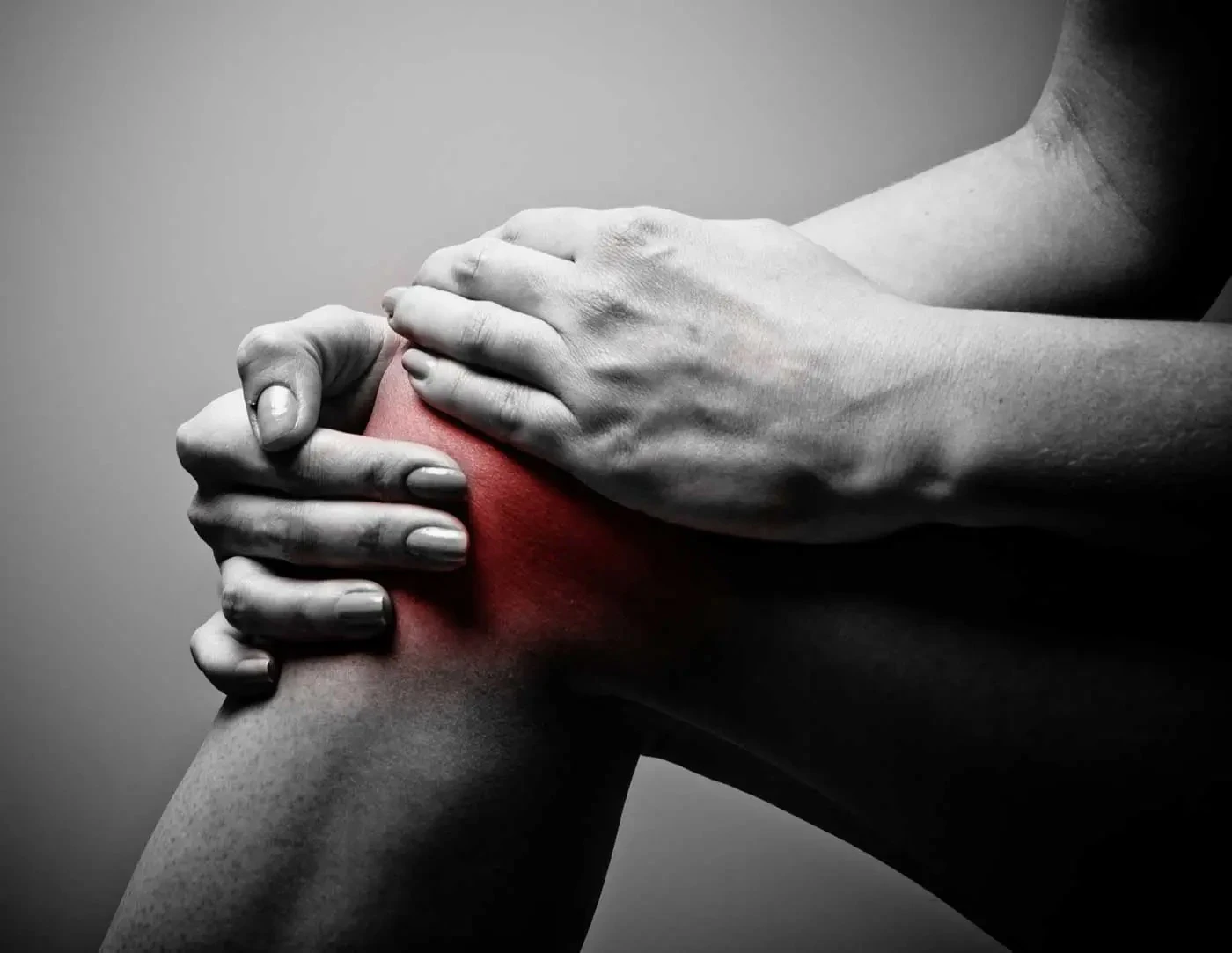 A patient holding her knee, with inflammation and pain indicated in red